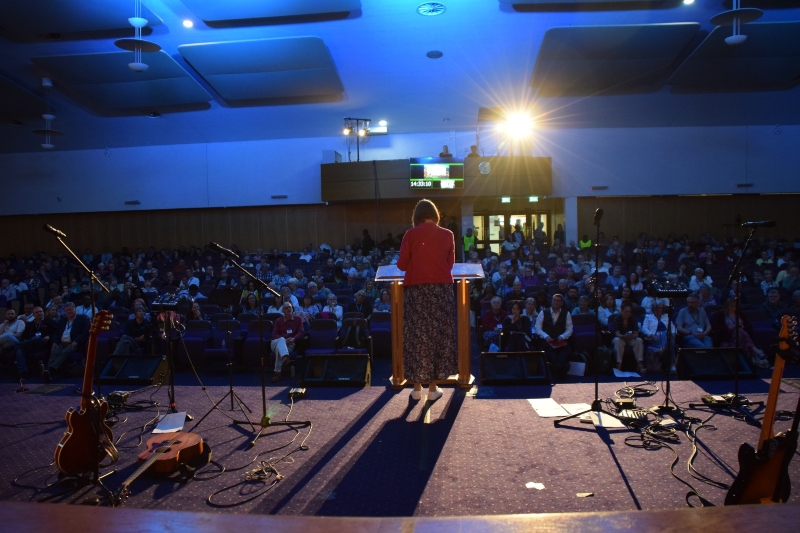 A shot from the back of the stage where Lynn Green is speaking, showing the crowd looking on