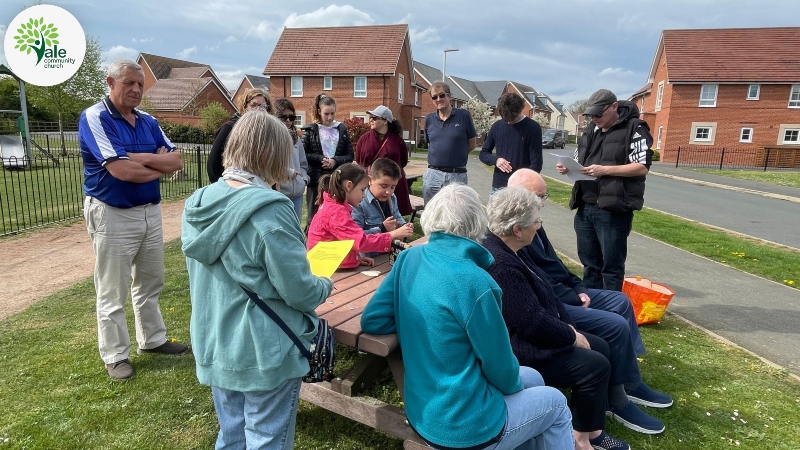 Small church gathering at an outside table and bench on a new housing estate 