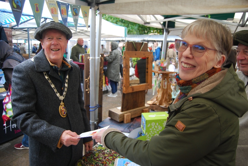 A man and woman are engaged in a cheerful exchange at the Fairtrade Stall at the local farmers' market