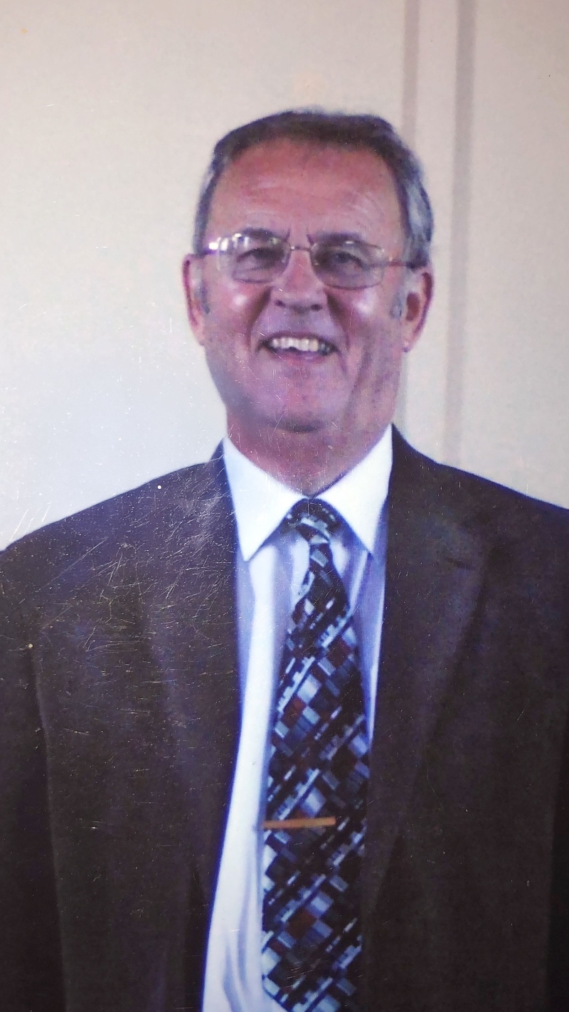 Graham J Rowles, wearing glasses and a suit and a tie, smiling