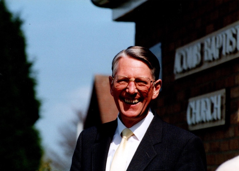 Tim Evans, smiling, wearing a suit on a sunny day, stood outside Acomb Baptist Church