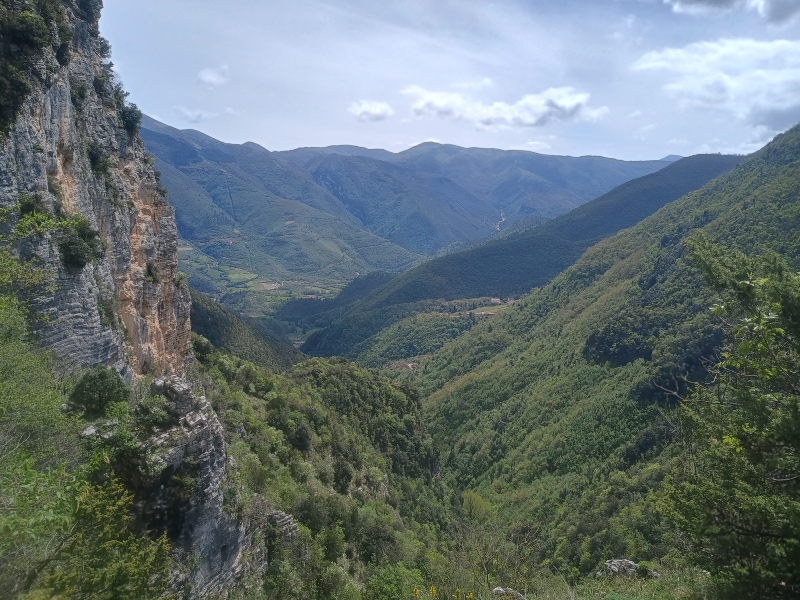 Spoleto Valley - A scenic panoramic view looking down into a deep, lush green mountain valley flanked by steep rocky cliffs under a bright sky