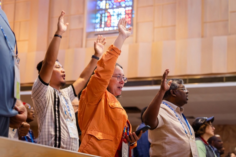 Members of a diverse church congregation standing with raised hands in worship during a service